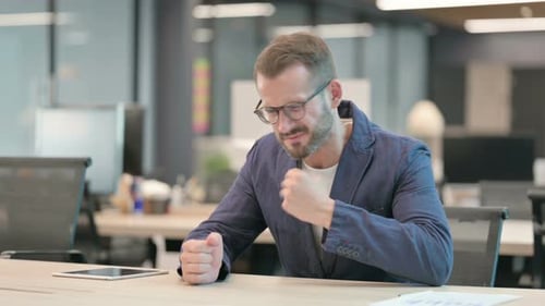 Upset Middle Aged Businessman Worried While Sitting in Office
