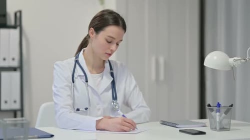 Female Doctor Writing at Desk in Office