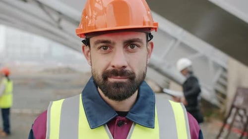 Portrait of Young Man Engineer Standing Outdoors in Workplace Smiling Looking at Camera