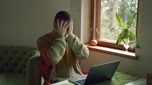 Stressed Man with Laptop at Table Indoors