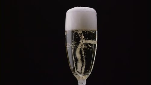 Glass of Champagne with a Rotating Bubbles Inside, Black Background, Close Up