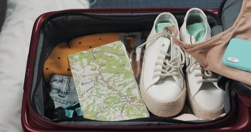 Woman's Hands Packing Suitcase for a Journey on the Bed at Home. Travel Preparations