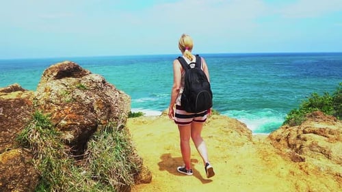 fille voyageuse marchant le long de la côte de la mer tropicale. beau paysage marin avec des rochers