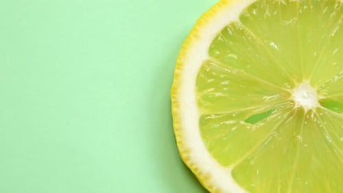 Slice of lemon rotating close-up on green background