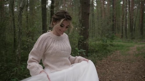 A Young Cheerful and Joyful Bride in a Wedding Dress and a Delicate Sweater Runs and Spins