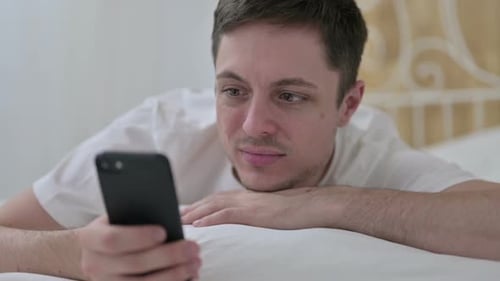 Close Up of Young Man Using Smartphone in Bed