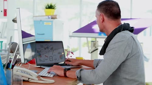 Man Working at Desk with Computer and Laptop