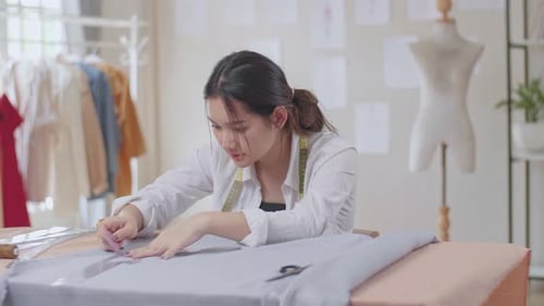 Young Woman Fashion Designer Tracing Pattern in Studio