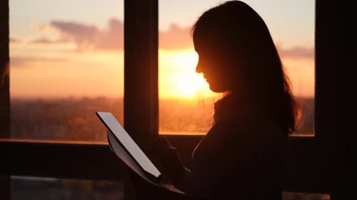 Woman Using Tablet in Silhouette at Sunset