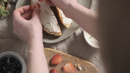 Top Down View Woman or Girl Decorate Croissants with Strawberry on Soft Cheese