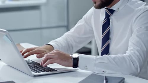Man Typing on Laptop in Bright Office