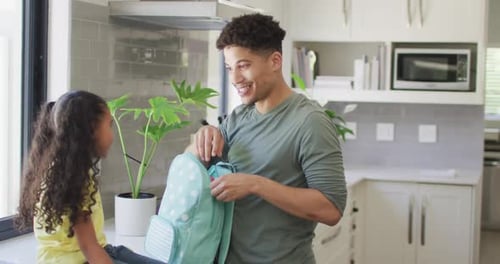 Happy biracial father and daughter packing lunch for school