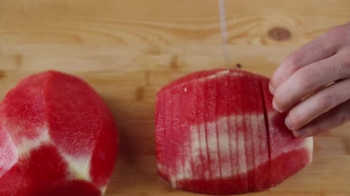Hands Slicing A Peeled Red Seedless Watermelon On The Chopping Board With A Sharp Knife - overhead s