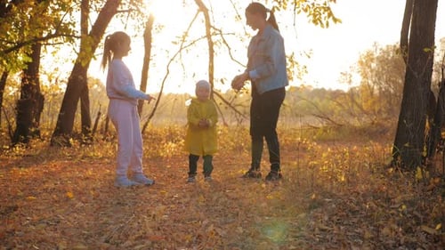 Mother and Two Children Walking in the Park and Enjoying the Beautiful Autumn Nature