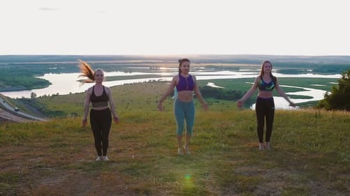 Young Women Exercising in Field at Sunset
