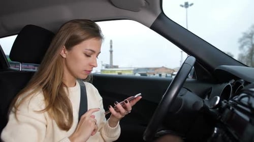 A Young Girl Reads a Message in the Phone She is in the Car