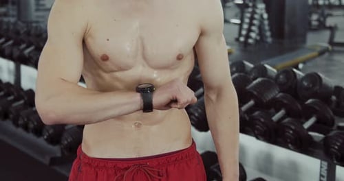 Muscular Man Checks Smart Watch at the Gym