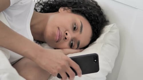 Woman Lies in Bed Using Smartphone