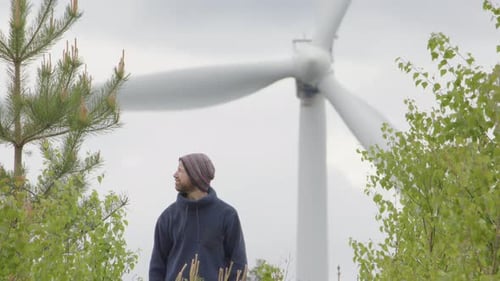 ENERGÍA EÓLICA - Un hombre barbudo mira las turbinas eólicas en un día ventoso. Contaminación acústica