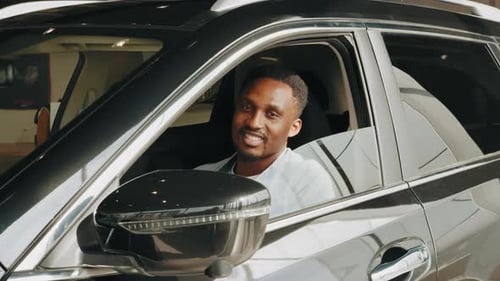 Excited African Man Showing a Car Key Inside His New Vehicle