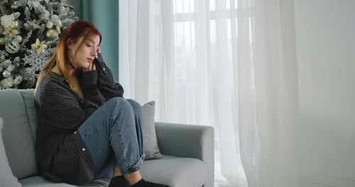 Lonely Young Woman Spending Christmas Alone. Portrait of Beautiful Redhead Caucasian Lady Sitting on