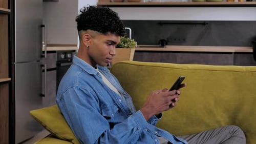 Young Adult Smiling Using Smartphone on Chartreuse Couch