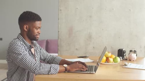 Smiling Young Adult Typing on Laptop at Home