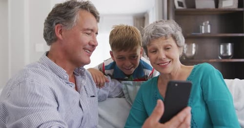 Grandparents and Grandson Enjoying Smartphone Together on Couch