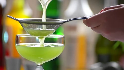 Green Beverage Pours Through Sieve