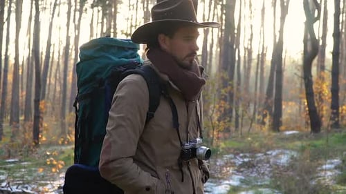 A Man with Camera Walks Along a Trail in the Forest