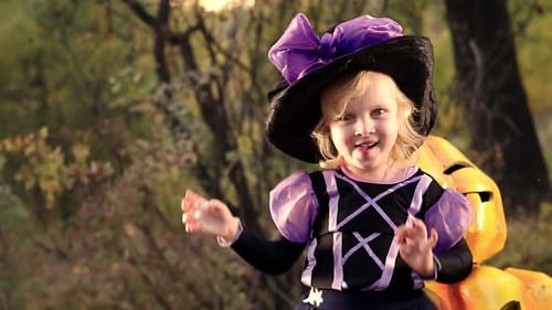 Girl in Witch Costume Poses Next to Pumpkin