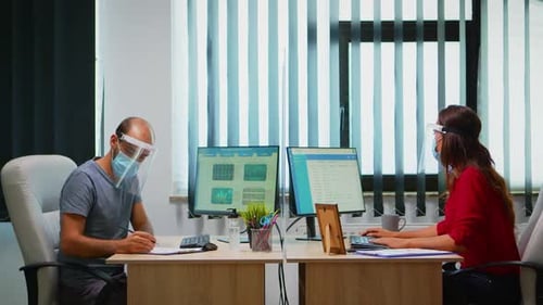 Office Workers Using Computers Wearing Masks and Shields