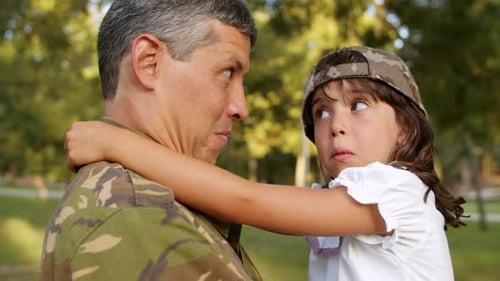 Happy Military Dad Putting Camouflage Cap on Daughter