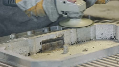 Klumpen der Hände eines Arbeiters beim Polieren eines Metallgussteils mit einer Schleifmaschine