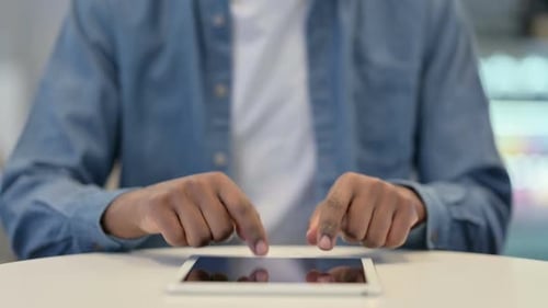 Close Up of African Man Typing on Tablet Kept on Table
