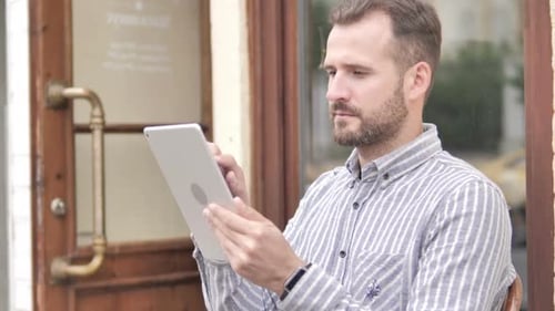 Man Using Tablet Outdoors Near a Building