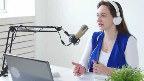Concept of Streaming and Broadcasting. Young Cheerful Girl in the Studio Speaks Into a Microphone