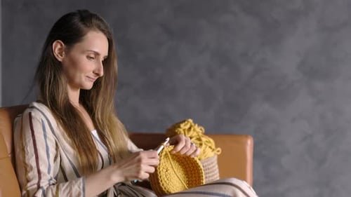 Woman Crocheting Yellow Yarn on Couch Indoors