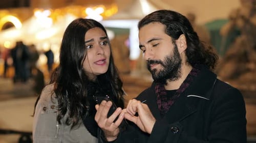 Couple Using Phone in City at Night