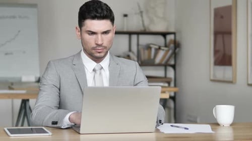 Man Works on Laptop in Bright Office