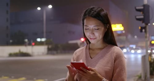 Woman look at mobile phone in city at night