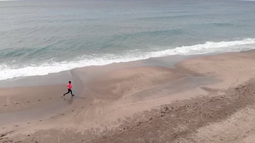 Strong young woman is running on stormy beach.