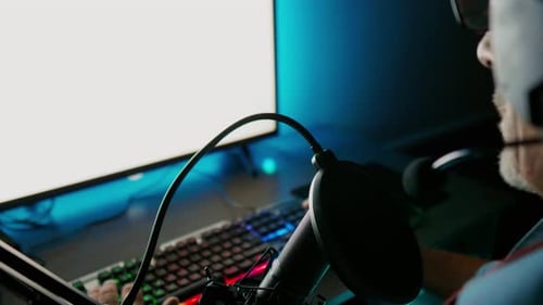 Senior man sitting in studio using computer and microphone