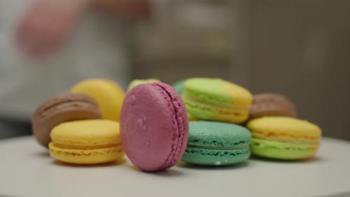 Stack of color merengue macaron cookies rotating on the plate. Close up of colourful macaron pile.