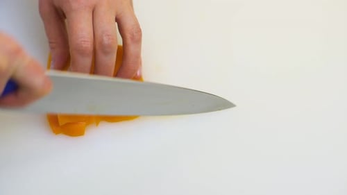 Chef Slices Yellow Bell Pepper in Kitchen