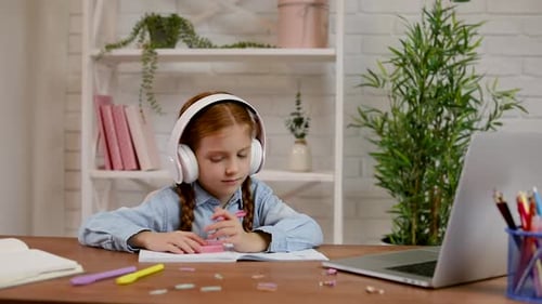 Young girl studies with headphones at home