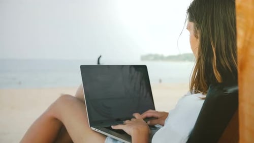 Rückansicht einer glücklichen erfolgreichen freiberuflichen Mitarbeiterin, die an mobilen Bürodiagrammen für Laptops arbeitet