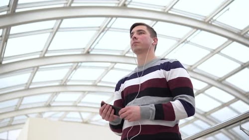 Young Man Using Smartphone with Headphones Indoors