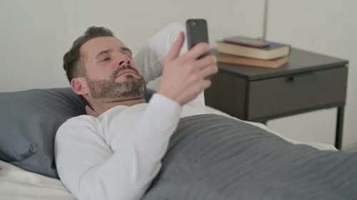 Man Lying in Bed Using Smartphone