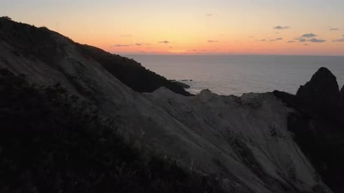 drone flight over a cliff into the sunset